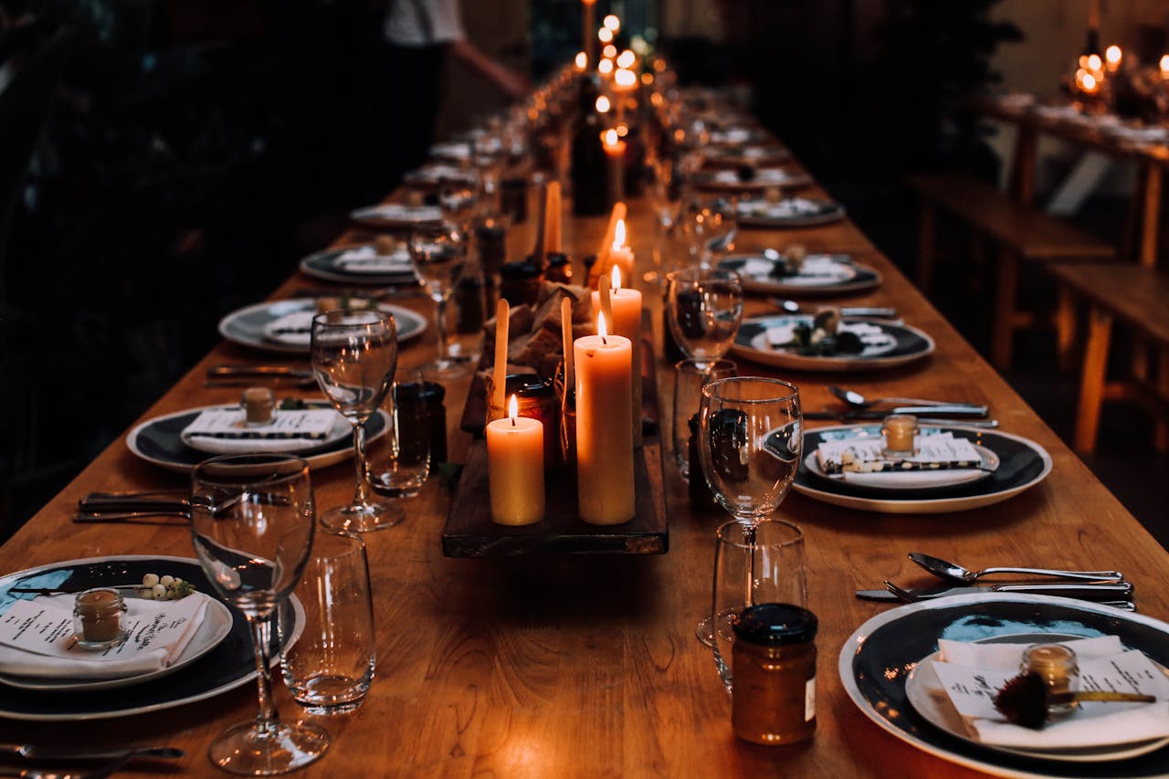 Long banquet table with elegant candlelit setting, featuring fine dining tableware.